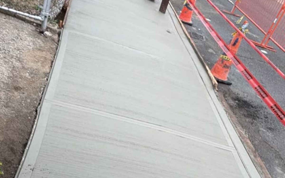 Completed sidewalk and curb reconstruction in freshly poured concrete along the Brunswick Ave frontage in Brooklyn