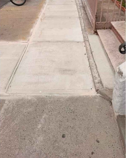 Level replacement concrete sidewalk outside 231 Calyer St in Brooklyn after repair