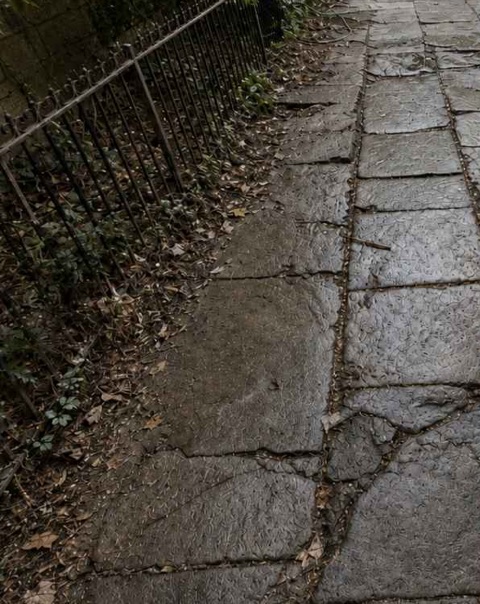 Uneven and cracked bluestone sidewalk flags outside 301 Clinton Street in Cobble Hill, Brooklyn, before restoration