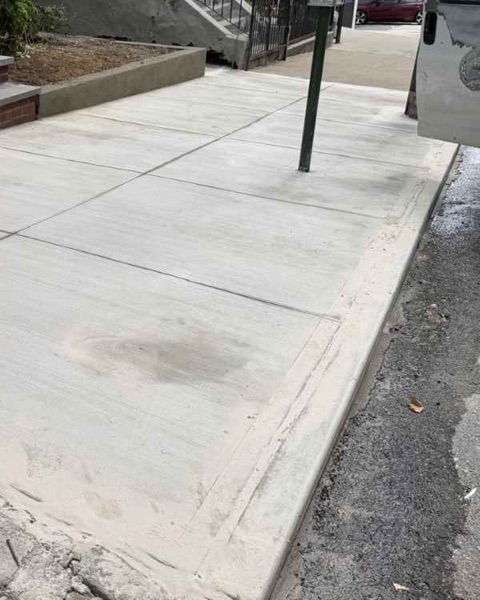 Newly poured sidewalk and rebuilt curb outside 954 Ogden Ave in Brooklyn after repair