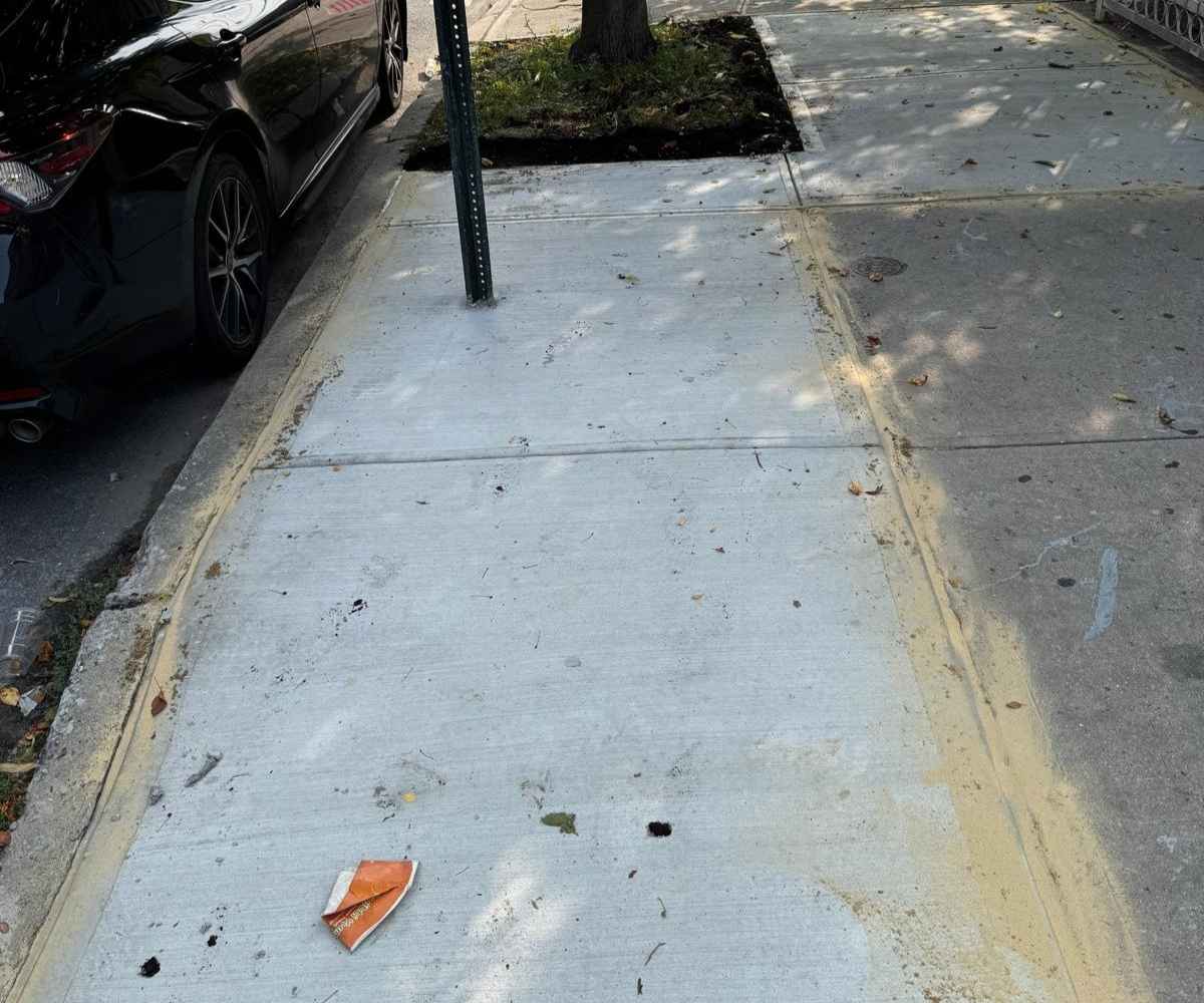 Completed concrete sidewalk replacement with a broom finish following tree-root damage repair at 117 MacDonough St in Brooklyn.