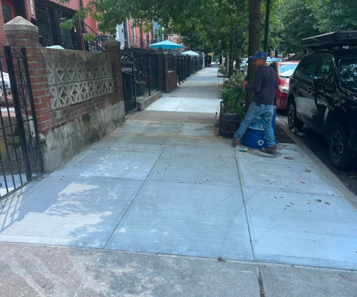 Newly replaced concrete sidewalk slabs after tree root damage repair and violation removal at 146 Hull St in Brooklyn, NY.