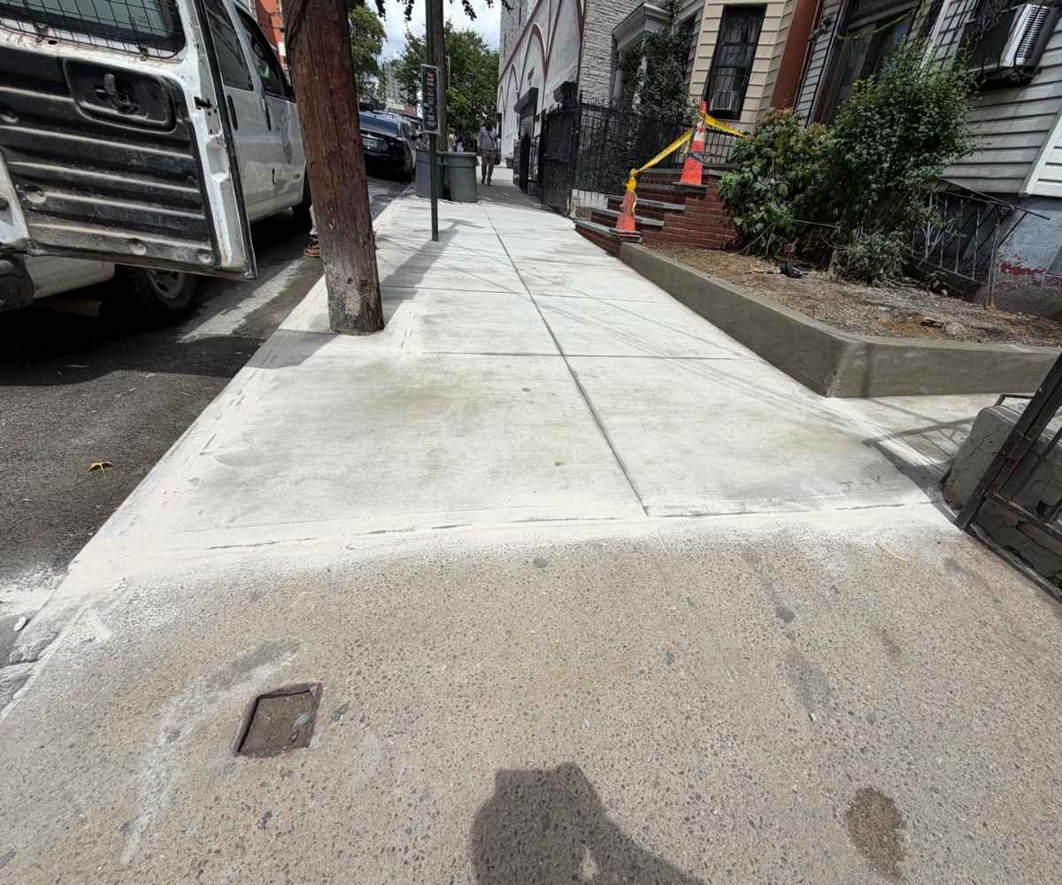 Completed sidewalk and curb restoration at 954 Ogden Ave in Brooklyn with newly poured concrete slabs