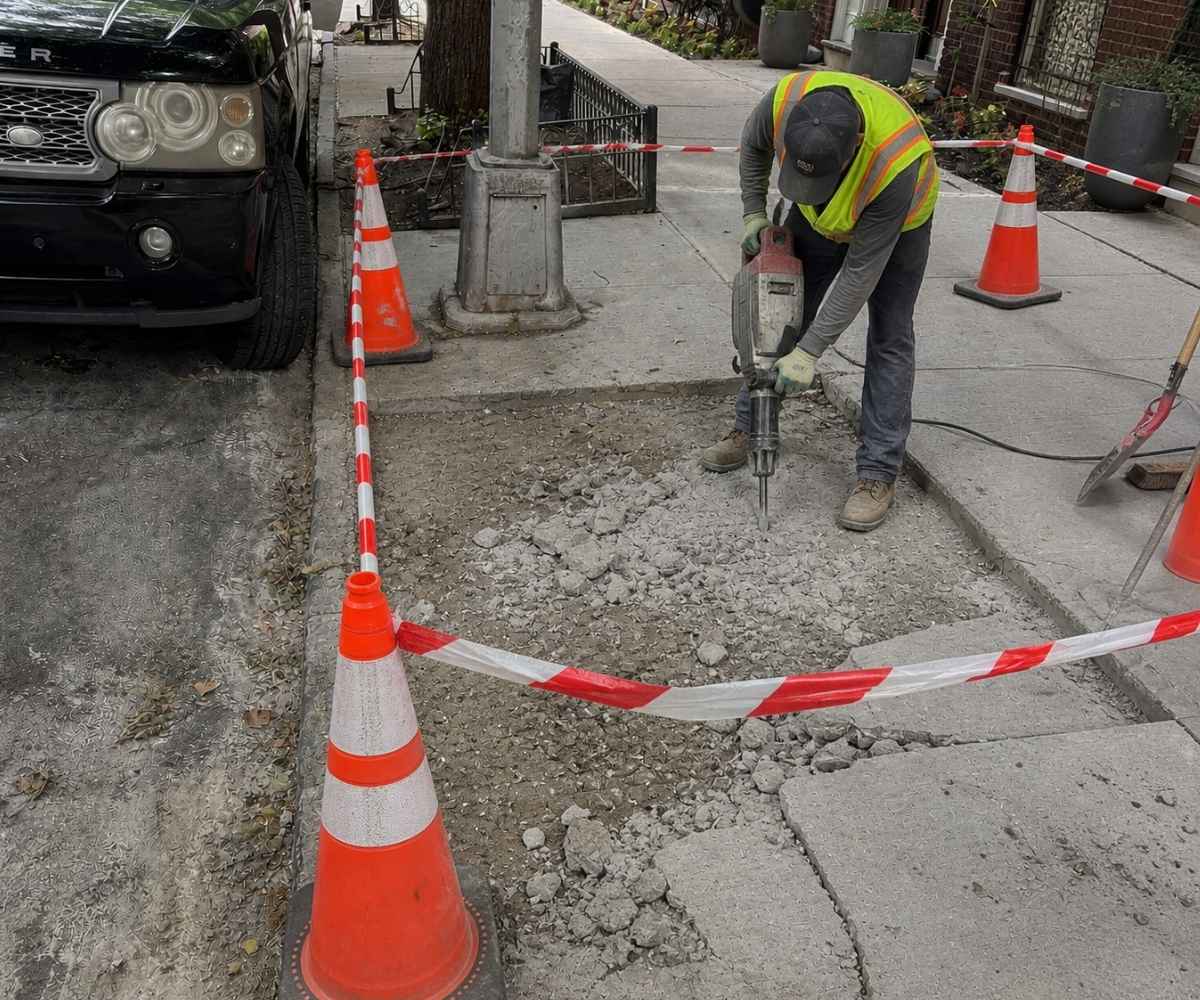 Sidewalk repair crew removing deteriorated concrete at 225 Park Pl in Prospect Heights, Brooklyn, before new sidewalk installation.